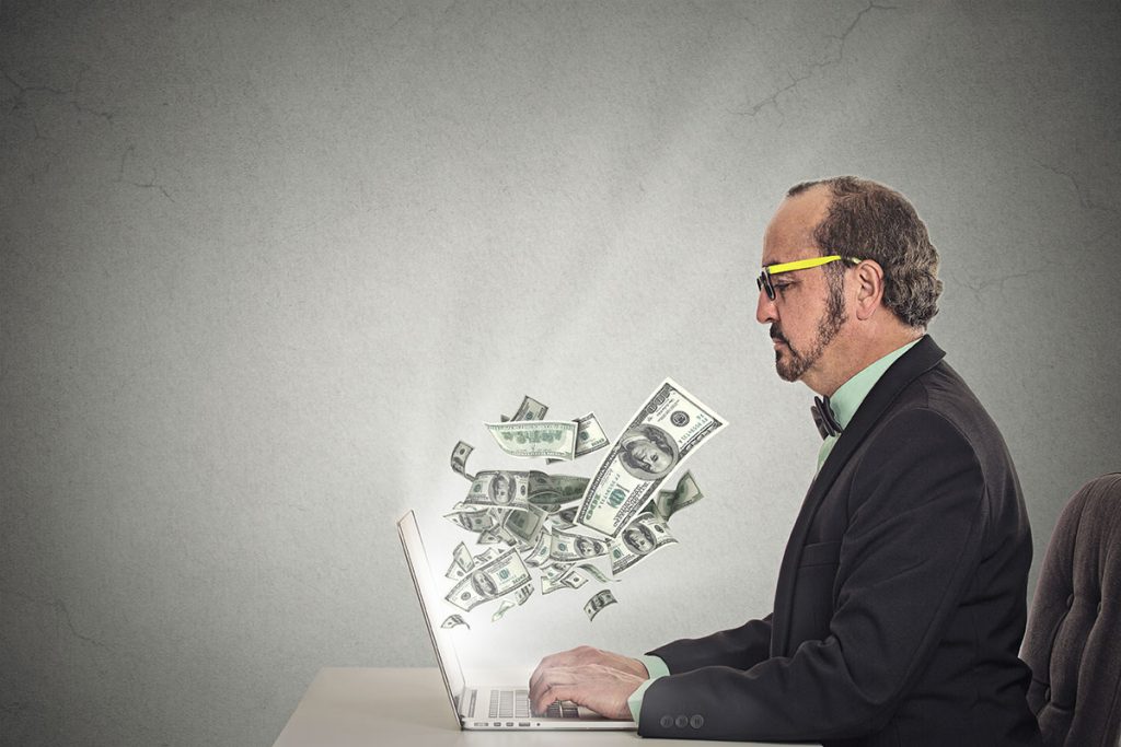 man with money flying out of his laptop