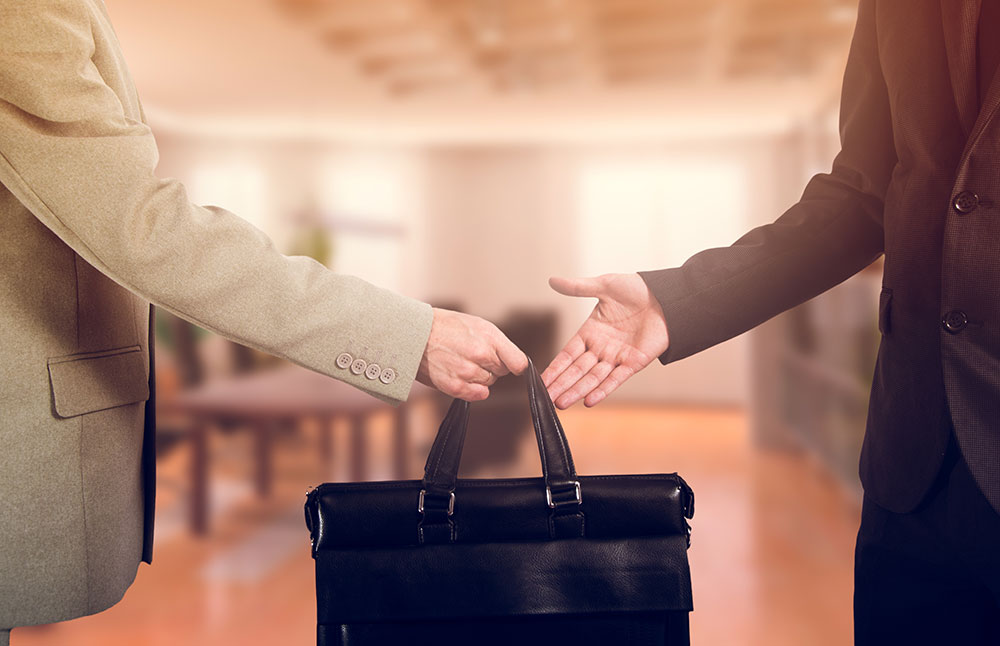 hands transferring briefcase