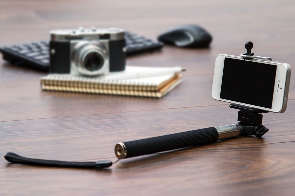 smartphone, selfie stick, camera, and notebook