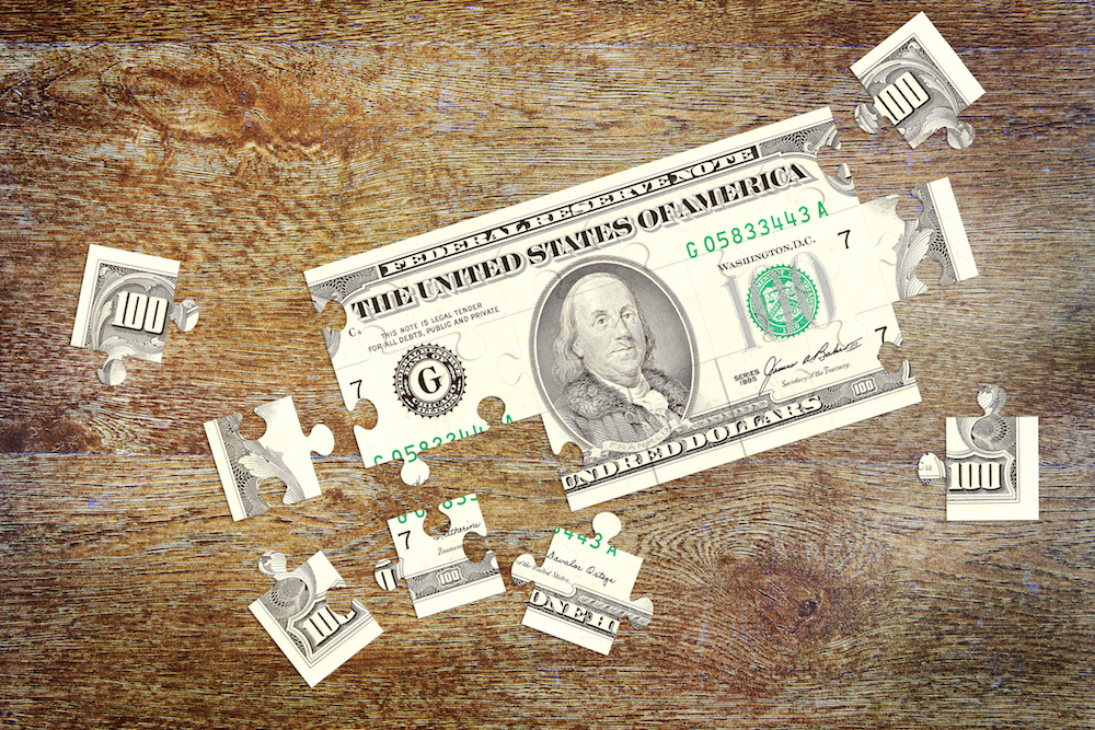 $100 bill cut into puzzle pieces