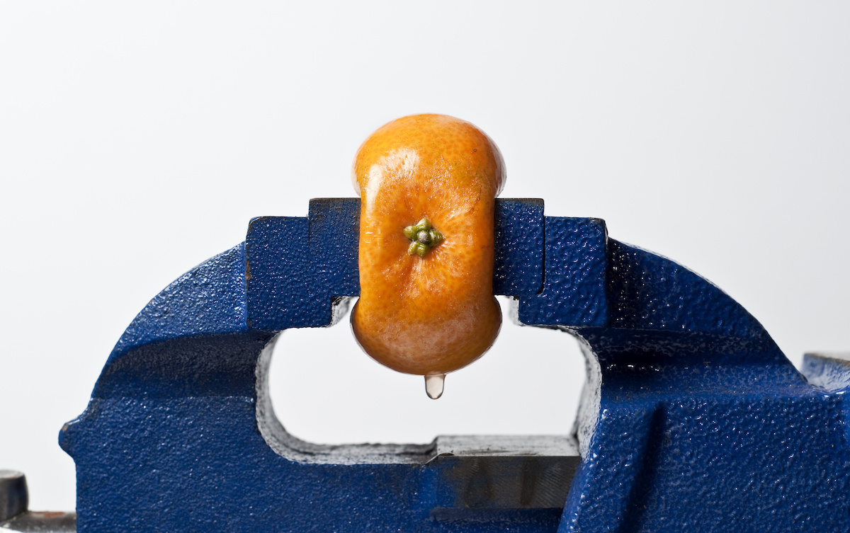 Orange being compressed in a vise