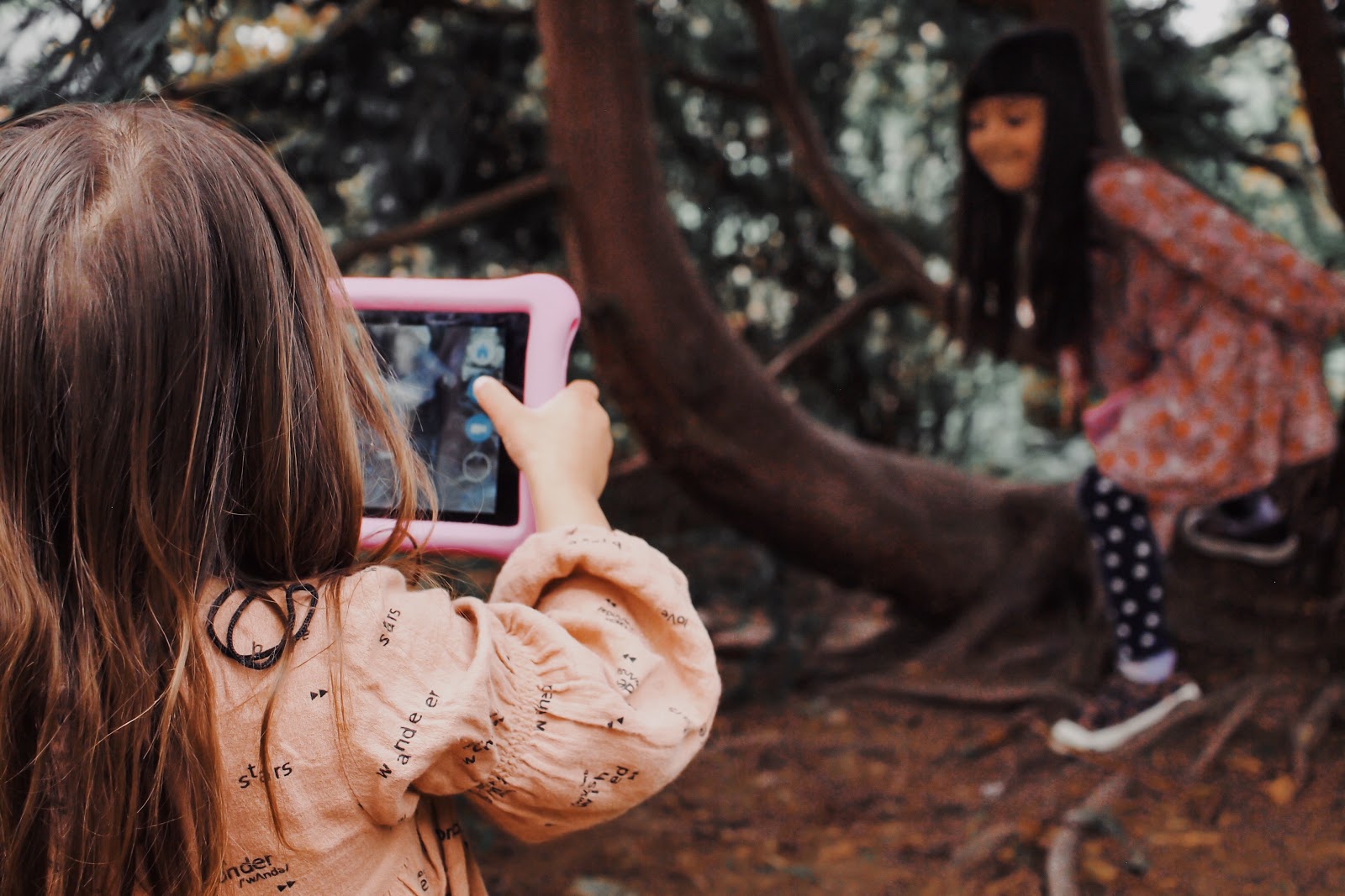 girl photographs sister with iPad