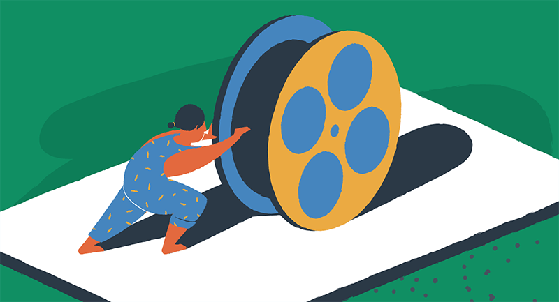 man rolling giant reel of film